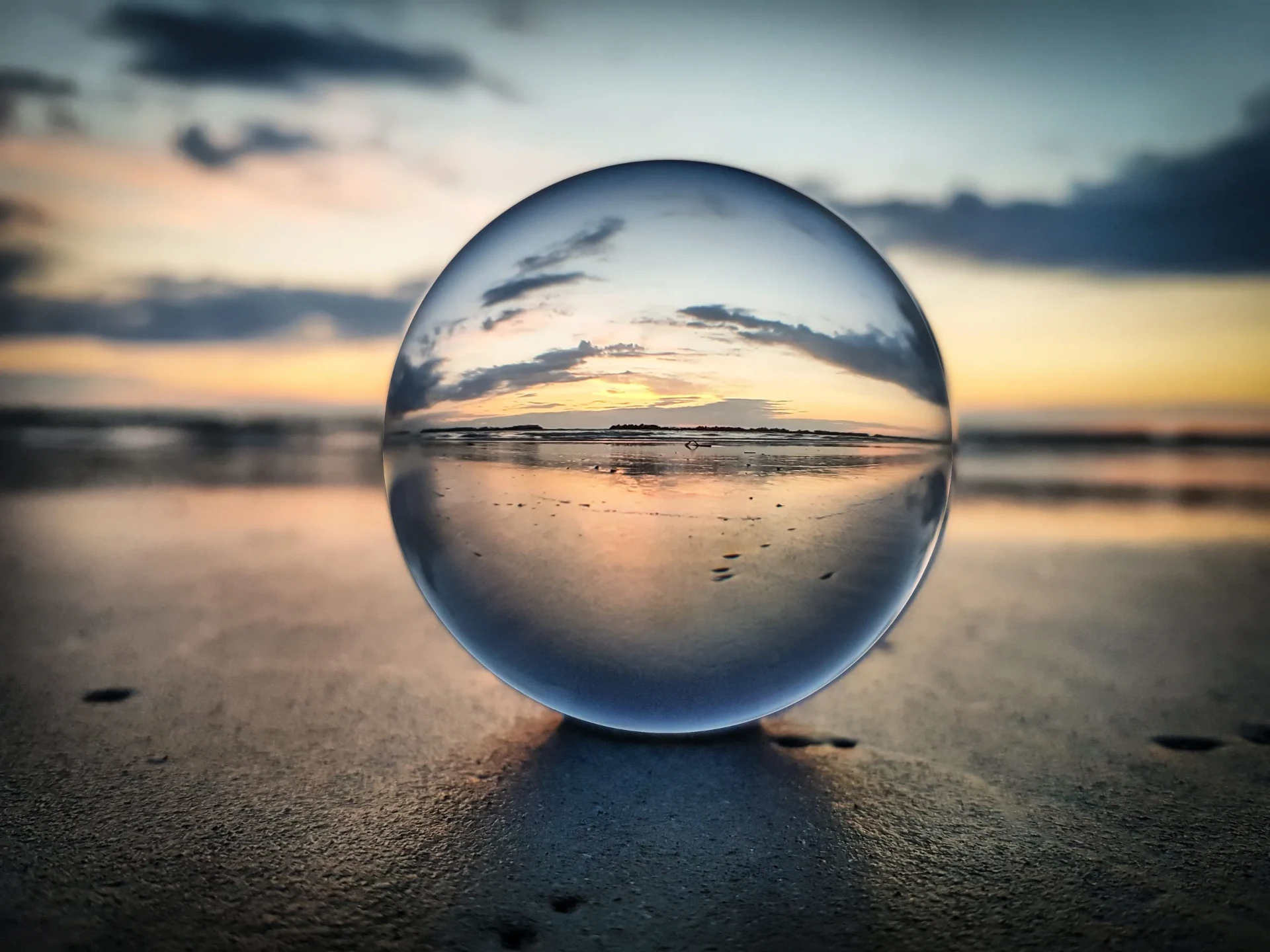 A glass sphere on the shore holding a clear view of the horizon